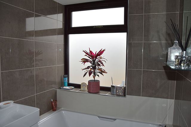 Solid dark woodgrain uPVC casement window in bahroom with frosted glass